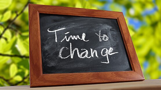 Kreidetafel auf der der Text "Time to change" geschrieben steht