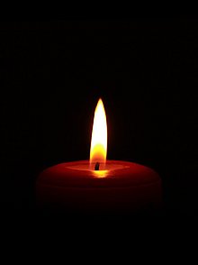 Eine einsame kleine Kerzenflamme in ansonsten vollständiger Dunkelheit