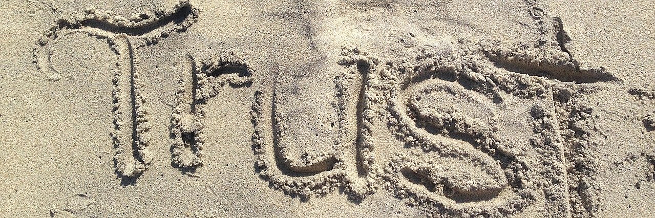 In den Sand ist das Wort "Trust" geschrieben