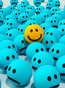 Ein sichtlich glücklicher gelber Smilie in einem Meer aus blauen schlecht gelaunten Smilies